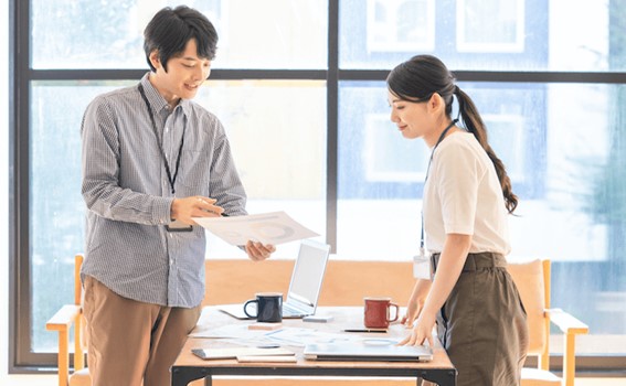 会議で使用する資料について、建設的な意見交換をする2人のビジネスパーソン