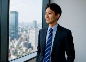 高層ビルから外を眺める30代若手コンサルタント