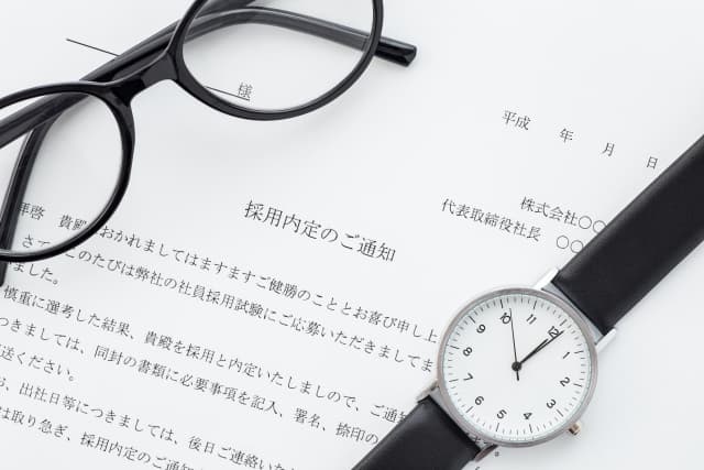 内定通知書の記載内容の一部と眼鏡と腕時計