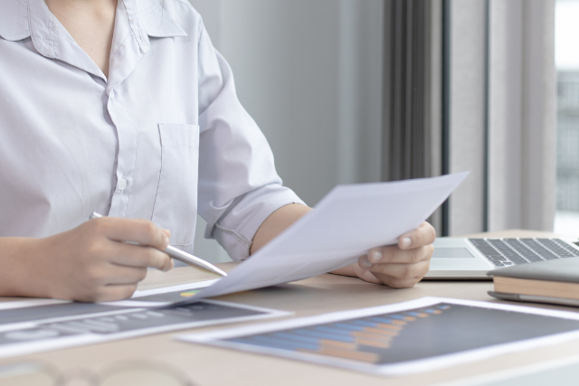 企業が社員のキャリア自律を促進するための準備資料を読み込む女性ビジネスパーソンの様子